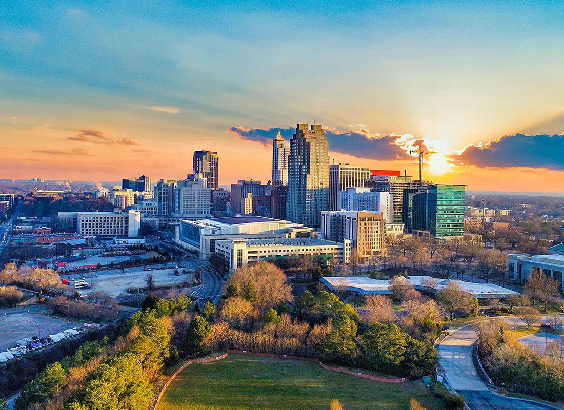 Rocky Mount, NC - Aerial View of Downtown Raleigh, North Carolina Skyline Displaying Tall Buildings and Trees During Sunset